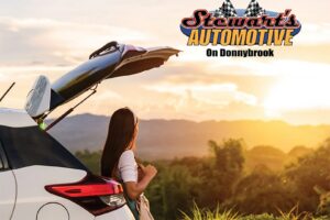 A girl in front of a white car with open back door. The picture has Stewart's Automotive logo.