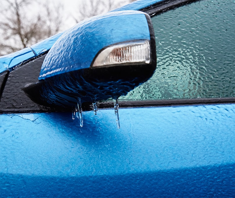 a blue car covered with ice - reminder of importance of seasonal auto maintenance in winter