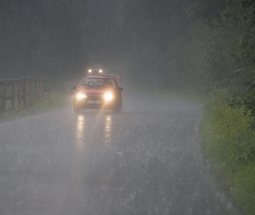 A car on the road in heavy rain with lights on