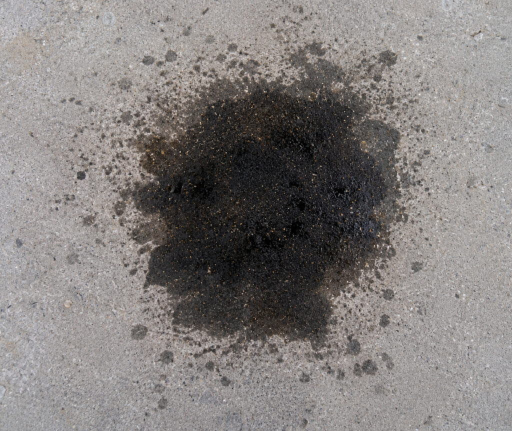 Close-up of dark oil stain on concrete driveway